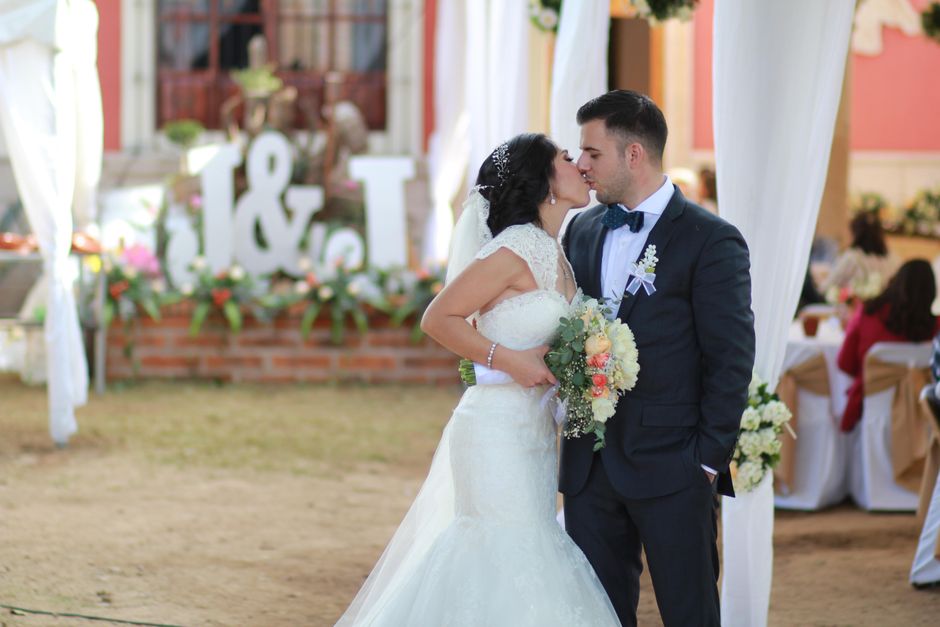 A bride and groom share a tender moment at their wedding ceremony held at the Spring Grove venue, with the bride holding a lush bouquet of fresh flowers featuring peach and white roses, eucalyptus, an